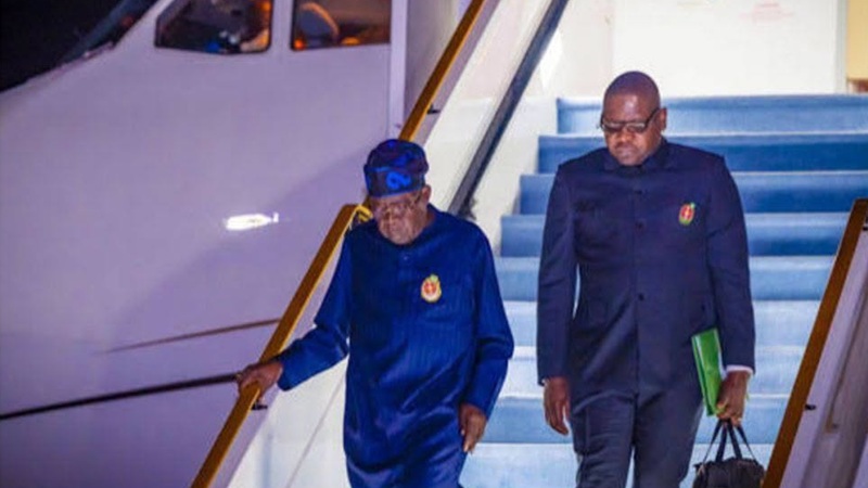 President Bola Ahmed Tinubu clutching the rail while coming down from aircraft as his left arm is visibly immobile
